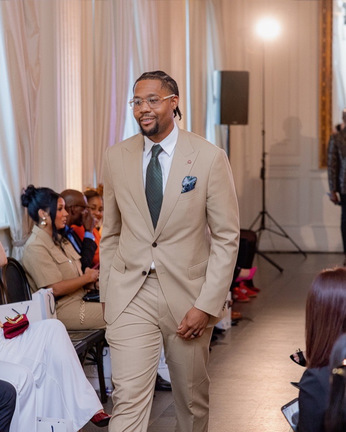 Troy “Magic” Osborne walking the room in a tan suit